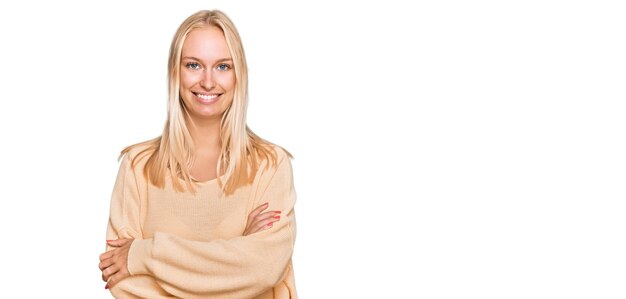 Giovane ragazza bionda che indossa abiti casual faccia felice sorridente con le braccia incrociate guardando la telecamera. persona positiva.