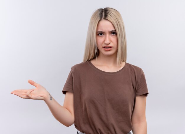 Giovane ragazza bionda dispiaciuta che mostra la mano vuota sulla parete bianca isolata