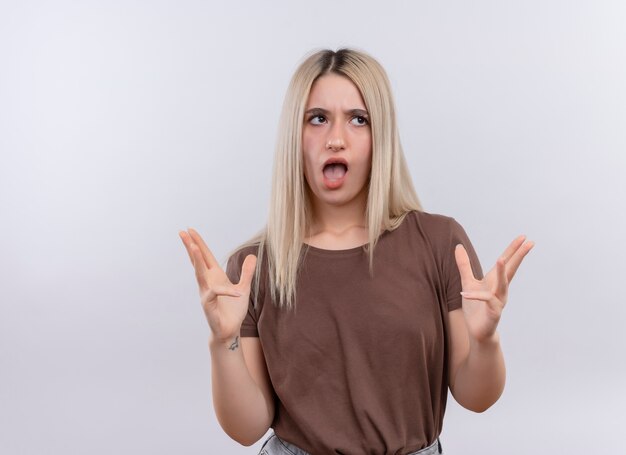 Giovane ragazza bionda infastidita guardando il lato destro con le braccia aperte e la bocca su uno spazio bianco isolato con spazio di copia