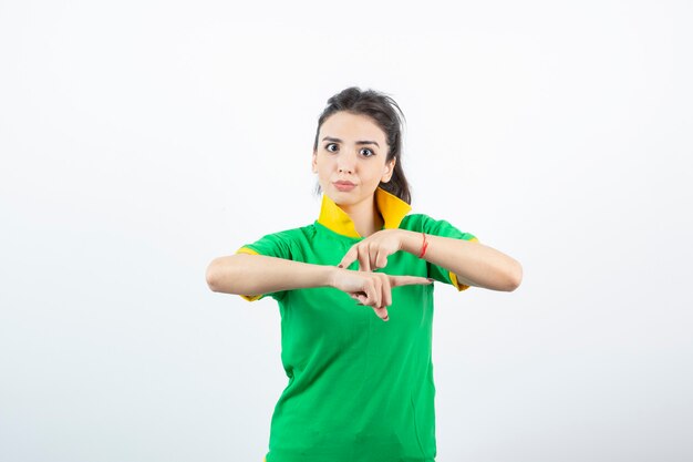 Giovane ragazza bruna in maglietta verde in piedi e alla ricerca.