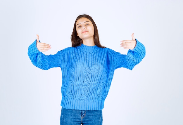 Giovane ragazza bruna in maglione blu in posa su bianco.