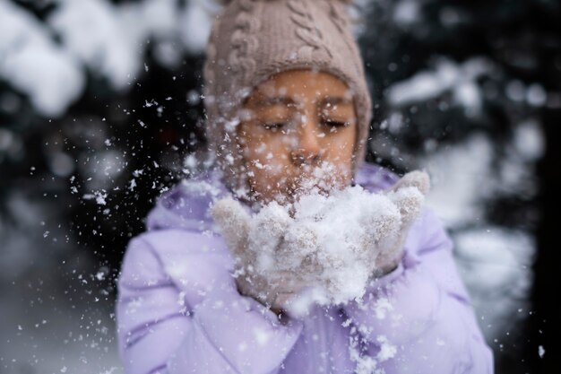 Giovane ragazza che gioca con la neve fuori in una giornata invernale