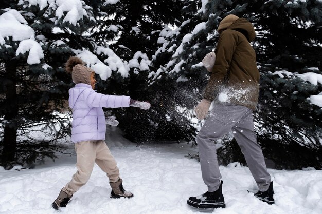 Giovane ragazza che ha una lotta sulla neve con suo padre in una giornata invernale