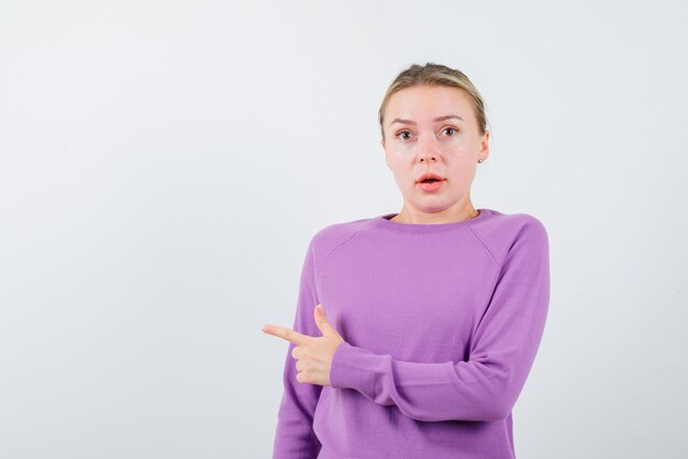 Giovane ragazza che mostra la sinistra con il dito su sfondo bianco