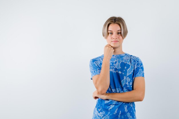 Giovane ragazza che tiene il pugno sotto il mento su sfondo bianco