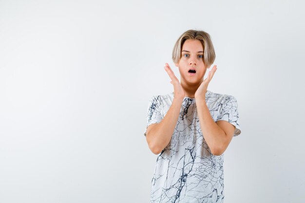 Giovane ragazza con la bocca aperta che tiene le mani vicino al viso su sfondo bianco