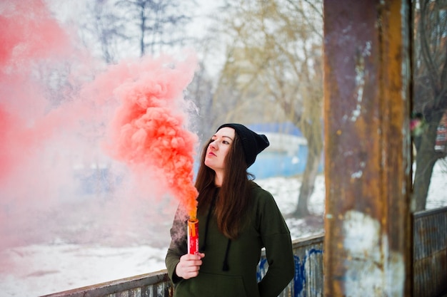 Giovane ragazza con una bomba fumogena di colore rosso in mano