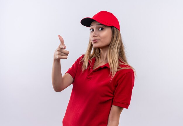 giovane ragazza di consegna che indossa l'uniforme rossa e cappuccio che mostra il gesto della pistola isolato sul muro bianco