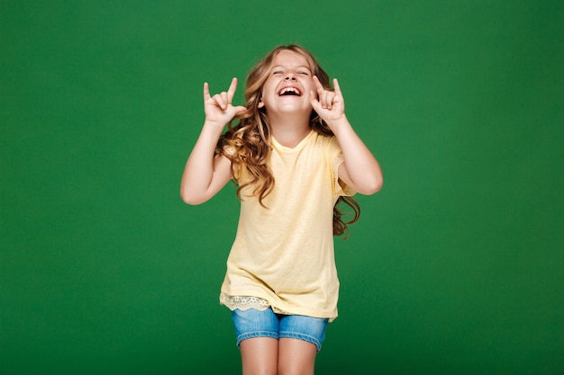 Giovane ragazza graziosa che ride sopra la parete verde