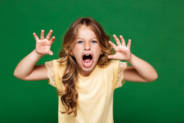 Giovane ragazza graziosa che spaventa sopra la parete verde