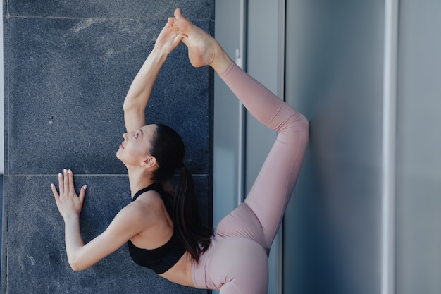 Giovane ragazza graziosa in abiti sportivi che fanno yoga