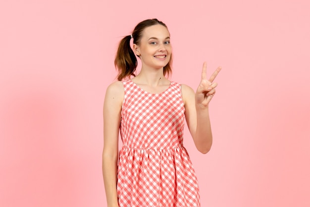 giovane ragazza in abito luminoso carino con felice espressione sul rosa