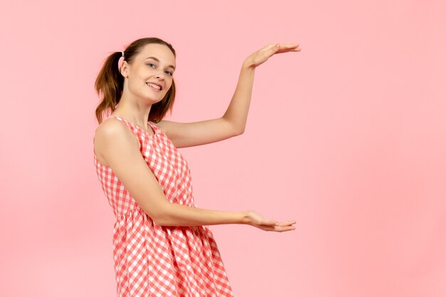 giovane ragazza in abito rosa carino con volto sorridente in rosa