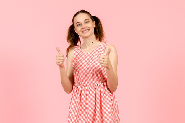 giovane ragazza in abito rosa carino in piedi e sorridente sul rosa