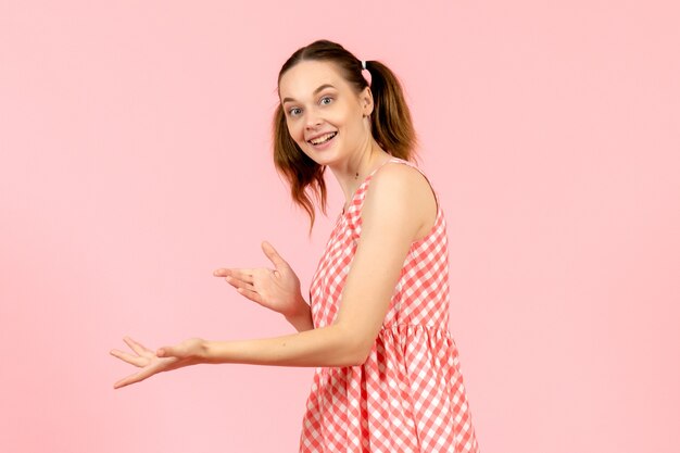 giovane ragazza in abito rosa carino sorridente sul rosa