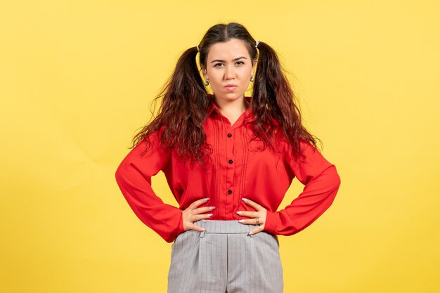 giovane ragazza in camicetta rossa in posa con il viso concentrato sul giallo