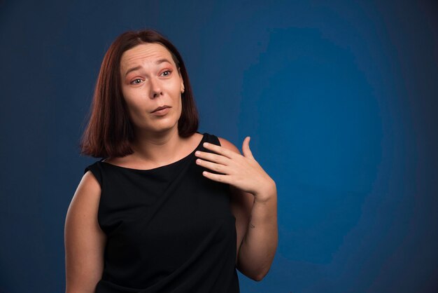 Giovane ragazza in camicia nera che punta a se stessa.