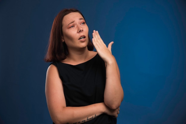 Giovane ragazza in camicia nera chiudendo la bocca.