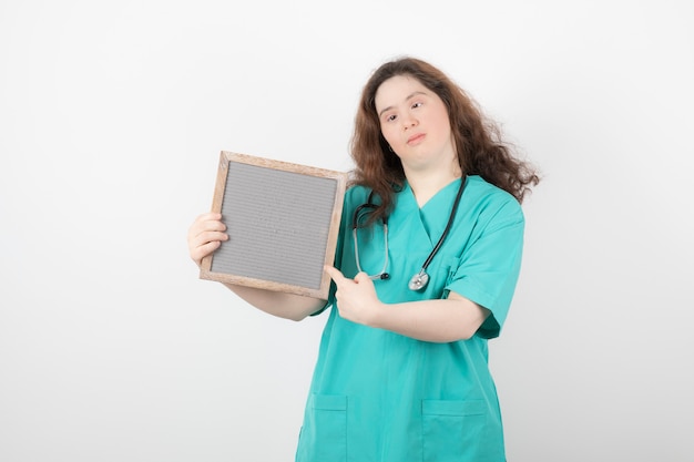 giovane ragazza in uniforme verde che punta a una cornice.