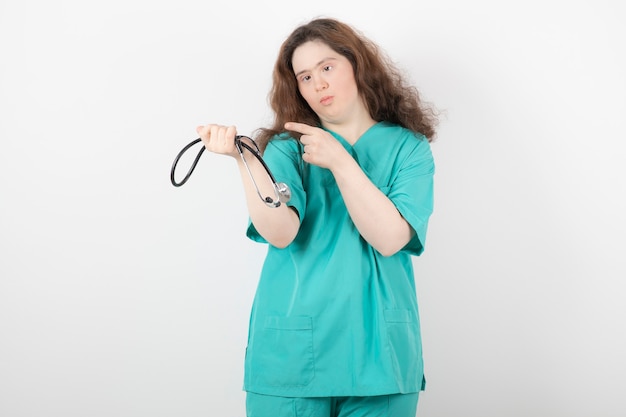 giovane ragazza in uniforme verde che punta allo stetoscopio