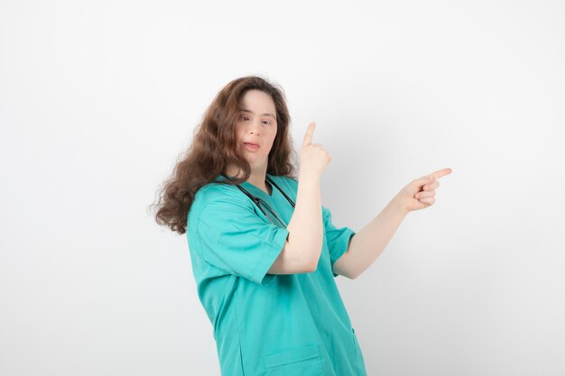 giovane ragazza in uniforme verde in piedi e che indica via.