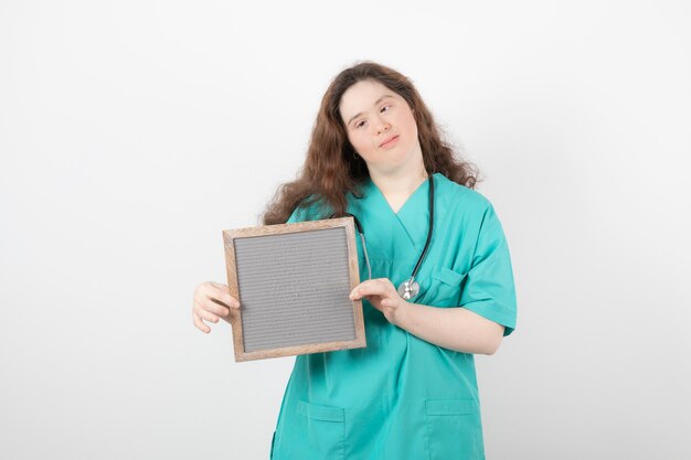 giovane ragazza in uniforme verde in possesso di un telaio.