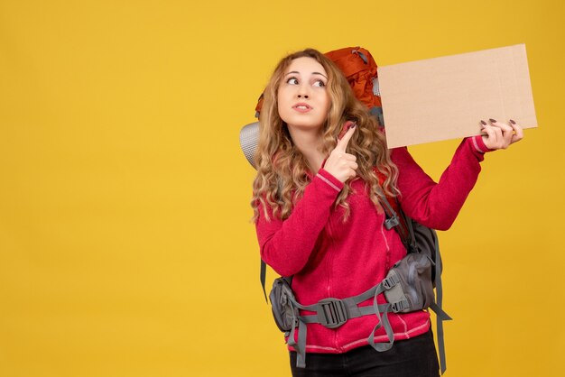 Giovane ragazza in viaggio raccogliendo i suoi bagagli che indica lo spazio libero per la scrittura