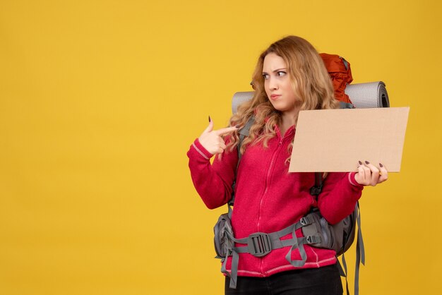 Giovane ragazza in viaggio sorpresa che raccoglie i suoi bagagli che mostra lo spazio libero per scrivere che indica se stessa