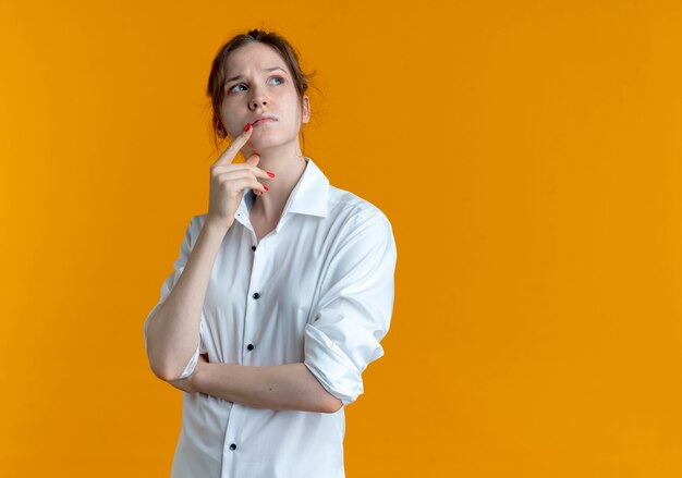 giovane ragazza russa bionda confusa mette la mano sul mento guardando a lato