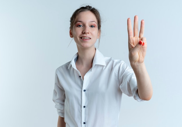 Giovane ragazza russa bionda felice gesti tre con le dita isolate su uno spazio bianco con spazio di copia