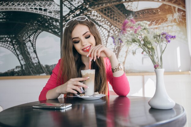 Giovane ragazza sorridente bere un frappè al cioccolato