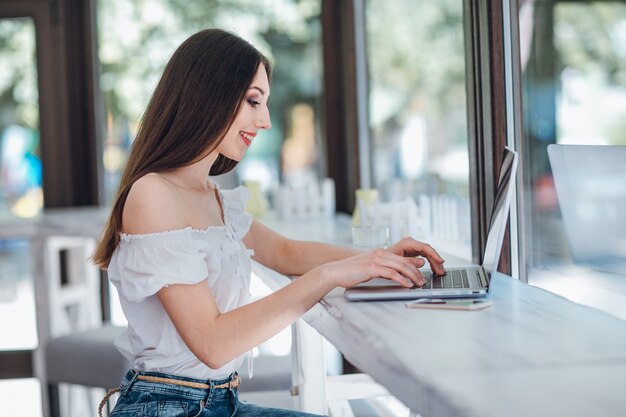 Giovane ragazza sorridente digitando su un computer portatile accanto