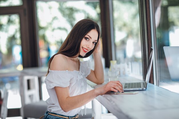 Giovane ragazza sorridente digitando su un computer portatile accanto