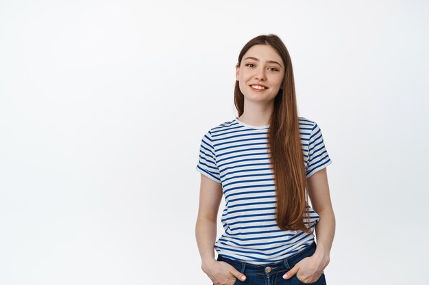 Giovane ragazza sorridente in maglietta a righe. Adolescente felice in piedi rilassato su sfondo bianco.