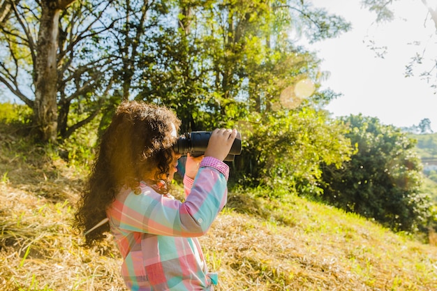 Giovane ragazza sulla collina con binocolo