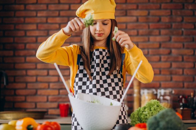 Giovane ragazza teenager che prepara insalata per la prima colazione alla cucina