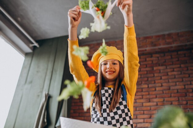 Giovane ragazza teenager che prepara insalata per la prima colazione alla cucina