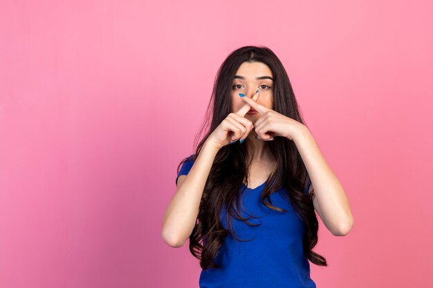 Giovane ragazza tenere il dito come una croce e guardando la fotocamera Foto di alta qualità