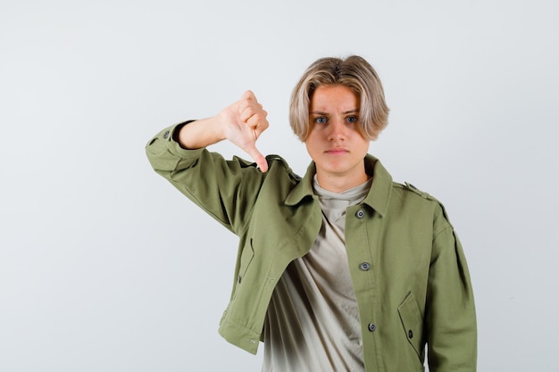 Giovane ragazzo adolescente che mostra il pollice in giù in t-shirt