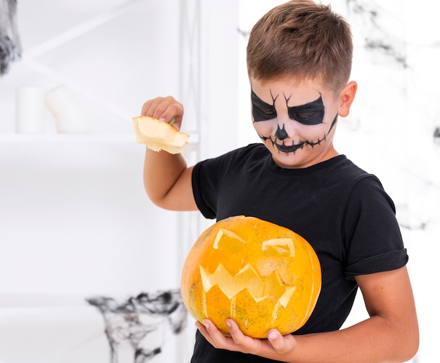 Giovane ragazzo adorabile che tiene zucca diabolica