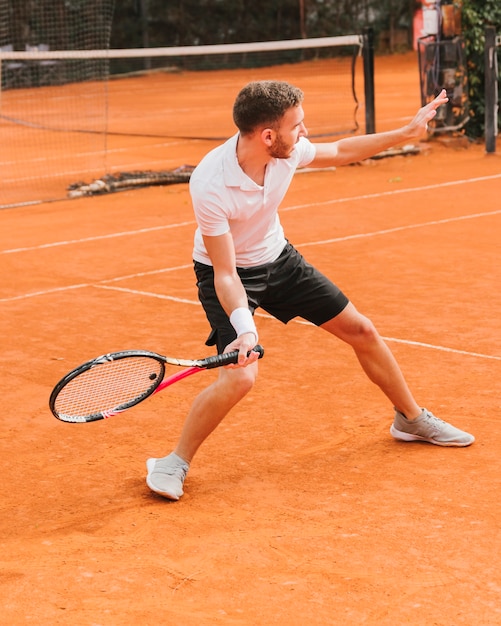 Giovane ragazzo atletico che gioca a tennis