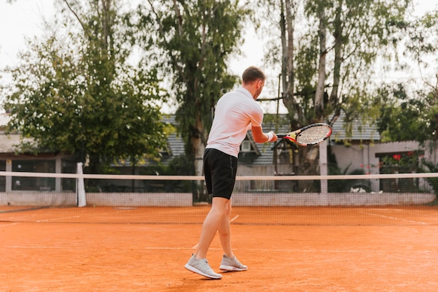 Giovane ragazzo atletico che gioca a tennis