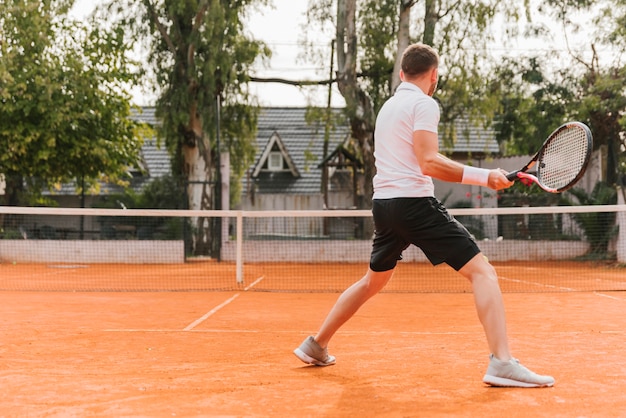 Giovane ragazzo atletico che gioca a tennis