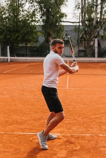 Giovane ragazzo atletico che gioca a tennis