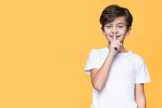 Giovane ragazzo che mostra segno per il silenzio