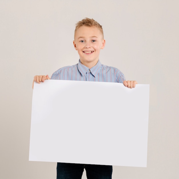 Giovane ragazzo che tiene carta in bianco