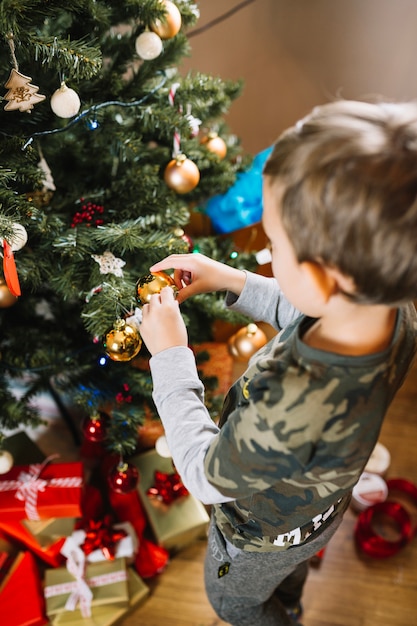 Giovane ragazzo decorare albero di natale