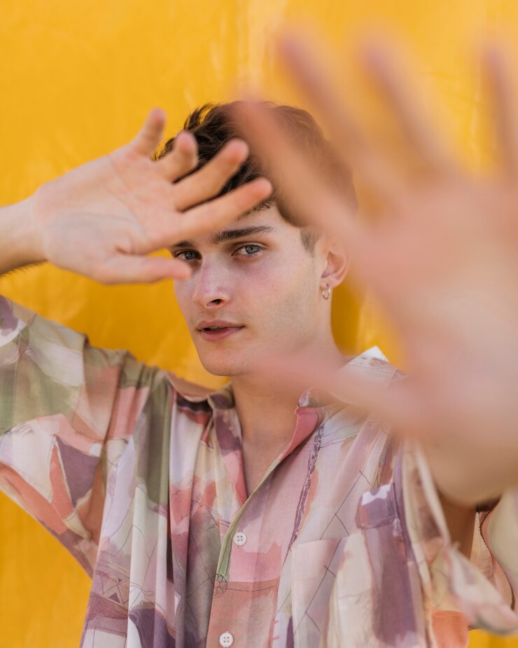 Foto gratuito giovane ragazzo del colpo medio che posa con il fondo giallo