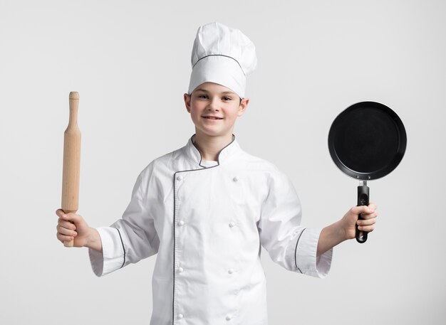Giovane ragazzo di vista frontale agghindato come strumenti di tenuta del cuoco unico