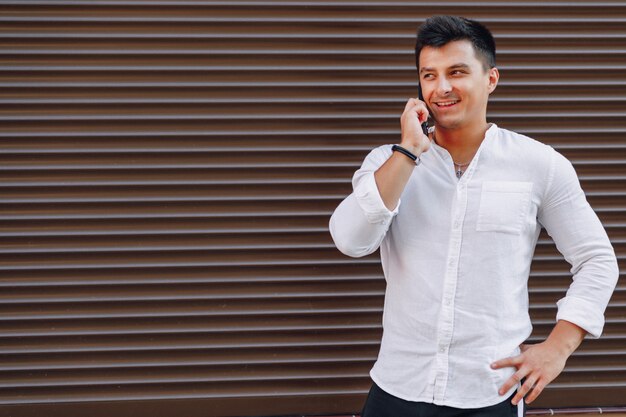 Giovane ragazzo elegante in camicia parlando al telefono